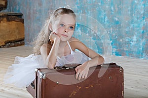 Little adorable ballerina in white tutu with old vintage suitcas