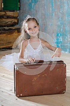 Little adorable ballerina in white tutu with old vintage suitcas