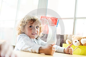 Little adorable boy sitting at table with milkshake in cafe