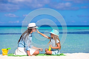 Little adorable girl applying sun cream to her