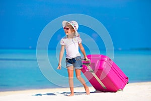 Little adorable girl with big bag on white beach