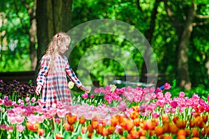 Little adorable girl in blooming tulips garden