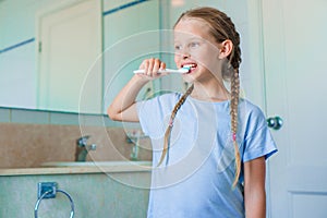 Little adorable girl brushes teeth in the bathroom. Perfect snow-white smile of little girl