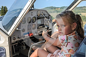 Little adorable girl child - pilot at the steering wheel of a light aircraft