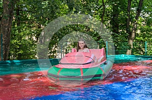 Little adorable girl child rides a boat in the amusement park