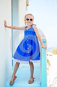 Little adorable girl in dress outdoors in old streets an Mykonos.