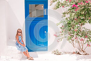 Little adorable girl in dress outdoors in old streets an Mykonos.