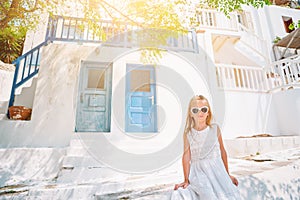 Little adorable girl in dress outdoors in old streets an Mykonos.