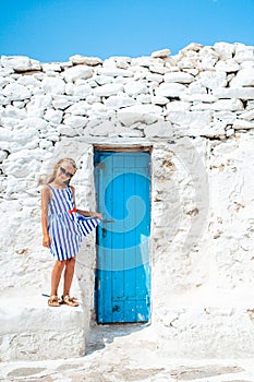 Little adorable girl in dress outdoors in old streets an Mykonos.