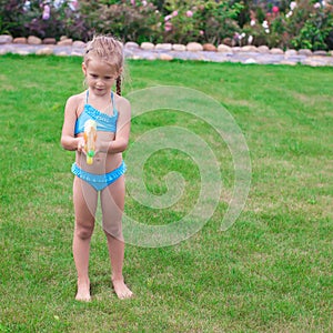 Little adorable girl playing with water gun