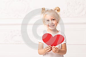 Little adorable girl prepares to give her heart-shaped car to someone