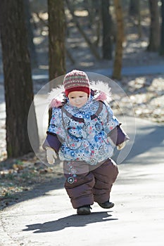 Little adorable girl toddling without help in cold weather park