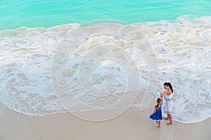 Little adorable girl and young mother at tropical beach with turquoise view from above
