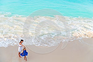 Little adorable girl and young mother at tropical beach view from above