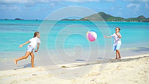 Little adorable girls playing with ball on the beach.
