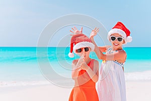 Little adorable girls in Santa hats during beach Christmas vacation having fun together