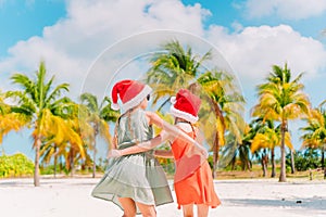 Little adorable girls in Santa hats during beach Christmas vacation having fun together