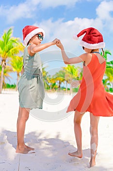 Little adorable girls in Santa hats during beach vacation have fun together