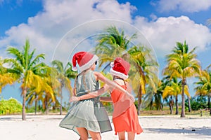 Little adorable girls in Santa hats during beach vacation have fun together