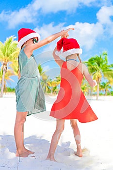 Little adorable girls in Santa hats during beach vacation have fun together