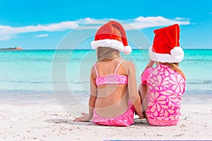 Little adorable girls in Santa hats during beach vacation have fun together