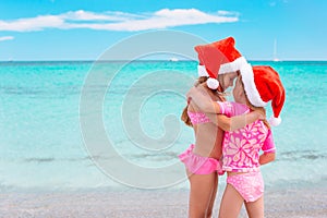 Little adorable girls in Santa hats during beach vacation have fun together