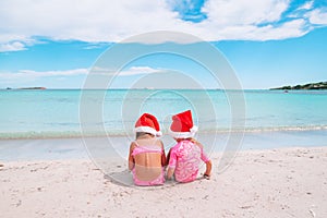 Little adorable girls in Santa hats during beach vacation have fun together