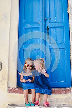 Little adorable girls sitting near old blue door