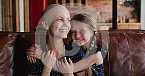 Little adorable loving daughter hug young bald mother cancer patient