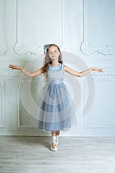 A little adorable young ballerina in a playful mood in the inter