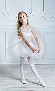 A little adorable young ballerina in a playful mood in the inter