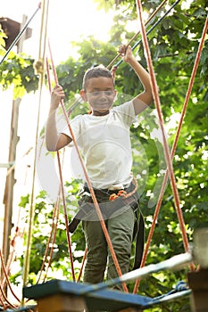 Little African-American boy climbing in adventure park