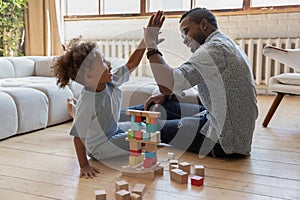 Little african american boy giving high five to smiling daddy.