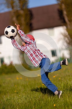 Little african american boy jump and trying to save soccer ball shooting at goal.Young football player goalkeeper on a grass