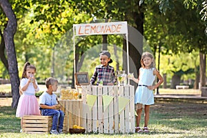 Little African-American boy selling lemonade at counter in park