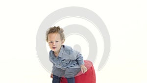 Little african american boy sits on a pillow in the studio. White background. Slow motion