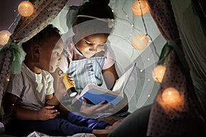 Little African-American children reading bedtime story in hovel photo
