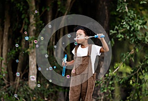 Little African American curly hair girl playing on park playground in spring or summer season. They enjoy climbing on the rope equ