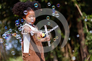 Little African American curly hair girl playing on park playground in spring or summer season. They enjoy climbing on the rope equ