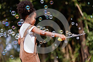 Little African American curly hair girl playing on park playground in spring or summer season. They enjoy climbing on the rope equ