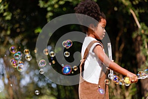 Little African American curly hair girl playing on park playground in spring or summer season. They enjoy climbing on the rope equ