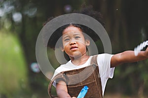 Little African American curly hair girl playing on park playground in spring or summer season. They enjoy climbing on the rope equ