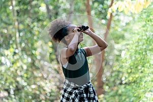 Little African American Girl with Binoculars during Hiking in Forest