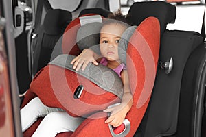 Little African-American girl in child safety seat inside