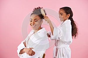Little African American girl is combing mother