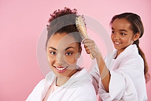 Little African American girl is combing mother