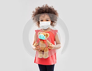 Little african american girl in mask with teddy