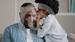 Little African American girl whispers in ear reveals secret to daddy daughter shares secrecy gossip confidential