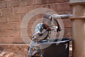 Little African Boy At The Community Borehole Quenching His Thirst