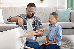 Little African Boy Helping Father Fix Table At Home